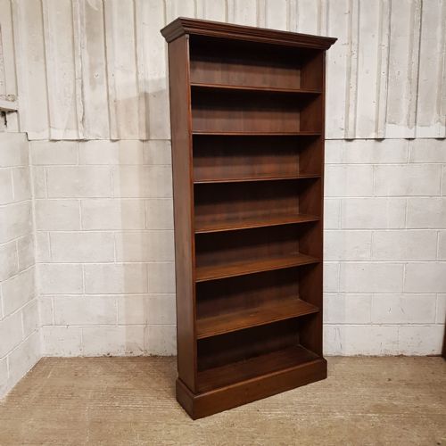 fig 2. A tall Edwardian dark oak open bookcase featuring eight fixed shelves, a top moulded cornice, and a sturdy plinth base.