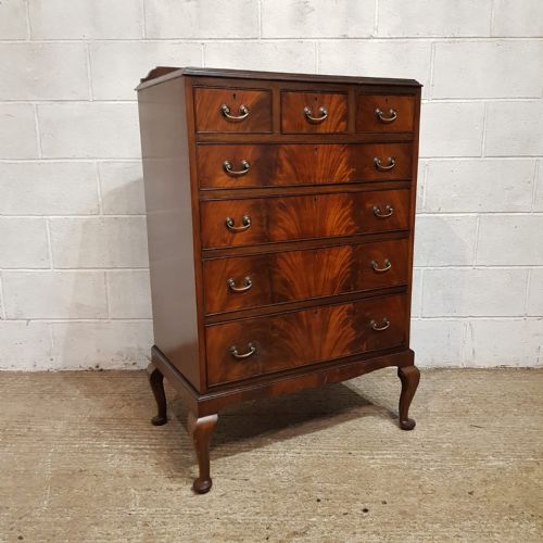 fig 1. A tall mahogany chest of drawers featuring flame mahogany veneer fronts, brass drop handles, and cabriole legs.