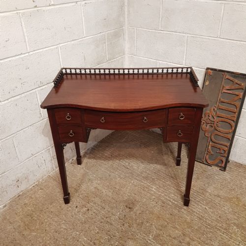 AN EDWARDIAN SERPENTINE FRONTED MAHOGANY WRITING TABLE C1900