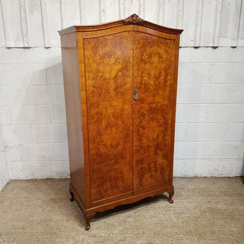 fig 1. A small 1920s burr walnut fitted wardrobe featuring double doors with book-matched grain, a carved top crest, and short cabriole legs.