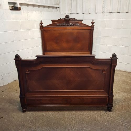 fig 1. A late 19th-century French double bed frame crafted from walnut and rosewood featuring a carved headboard crest and panelled detailing.