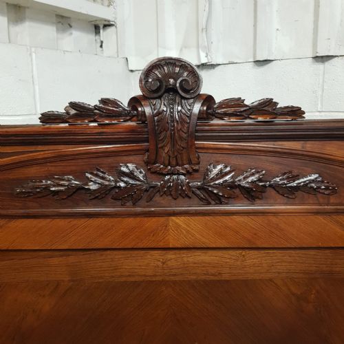 fig 2. A late 19th-century French double bed frame crafted from walnut and rosewood featuring a carved headboard crest and panelled detailing.