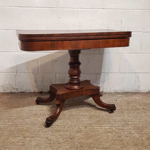 fig 2. A Regency mahogany fold-over table featuring a rounded rectangular hinged top on a central turned pedestal column with four splayed legs and brass castors.
