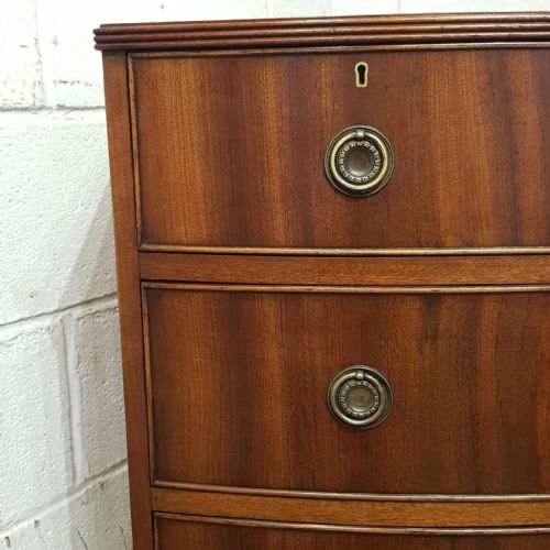fig 2. A small mahogany bow-fronted chest of drawers featuring two short drawers over two long drawers with brass ring handles.
