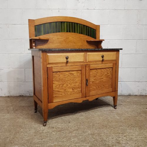 fig 3. A three-piece Edwardian oak bedroom suite comprising a double-door wardrobe with a tall arched mirror, a dressing chest with an oval tilting mirror, and a washstand featuring a dark marble top and green tile splashback.