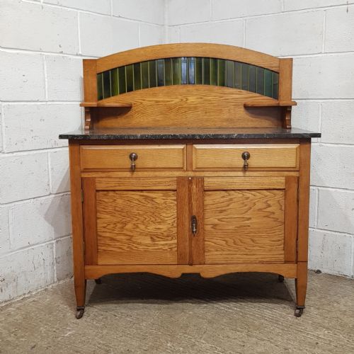fig 4. A three-piece Edwardian oak bedroom suite comprising a double-door wardrobe with a tall arched mirror, a dressing chest with an oval tilting mirror, and a washstand featuring a dark marble top and green tile splashback.
