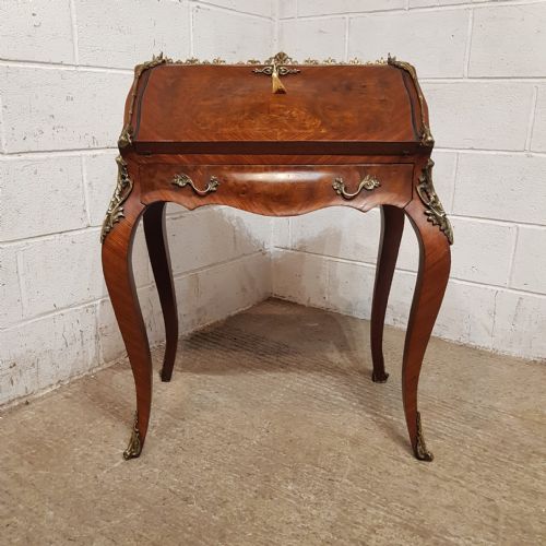 fig 1. A French Louis XV style walnut bureau de dame featuring cabriole legs, a slant-front lid with brass key tassel, decorative brass mounts, and a pierced top gallery.