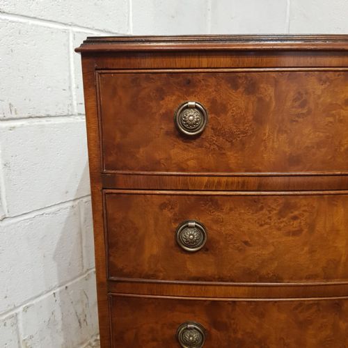 fig 1. A 1920s burr walnut chest of drawers featuring four graduated bow-front drawers with brass ring handles and bracket feet.