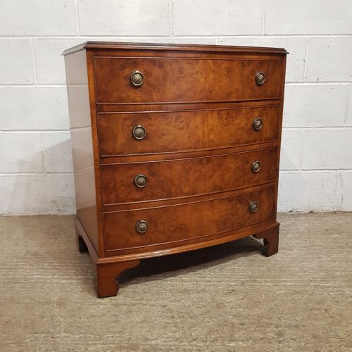 fig 2. A 1920s burr walnut chest of drawers featuring four graduated bow-front drawers with brass ring handles and bracket feet.