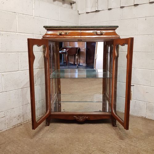 fig 1. A walnut vitrine cabinet featuring shaped glazed doors, gilt metal mounts, a green marble top, and a mirrored back interior.