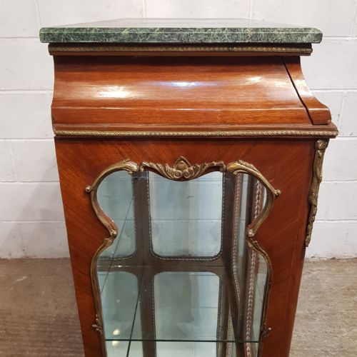 fig 2. A walnut vitrine cabinet featuring shaped glazed doors, gilt metal mounts, a green marble top, and a mirrored back interior.