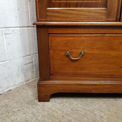 fig 1. An Edwardian mahogany double wardrobe featuring a central oval mirror door flanked by inlaid timber panels above two drawers.