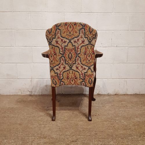 fig 2. A pair of 1920s walnut armchairs featuring patterned tapestry upholstery, cabriole front legs, and brass stud trim.