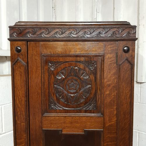 fig 1. A tall, narrow dark oak single-door hall wardrobe featuring a carved rosette panel and wave trim detail.