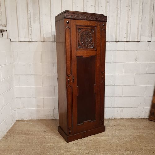 fig 2. A tall, narrow dark oak single-door hall wardrobe featuring a carved rosette panel and wave trim detail.