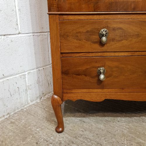 fig 1. A 1920s burr walnut tallboy featuring double cupboard doors with quarter-matched veneer above two drawers, supported by cabriole legs.