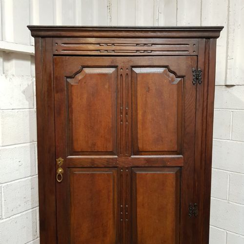 fig 1. A compact dark oak single-door wardrobe dating to circa 1920, featuring six recessed panels, carved detailing, and exposed decorative hinges.