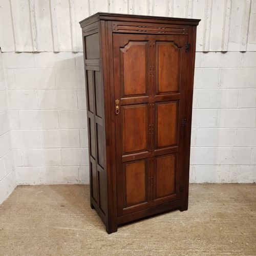 fig 2. A compact dark oak single-door wardrobe dating to circa 1920, featuring six recessed panels, carved detailing, and exposed decorative hinges.