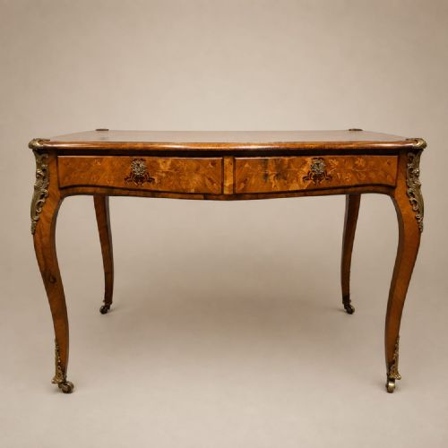 fig 1. A nineteenth-century French walnut writing desk featuring floral marquetry drawers, ornate gilt bronze mounts, and slender cabriole legs.