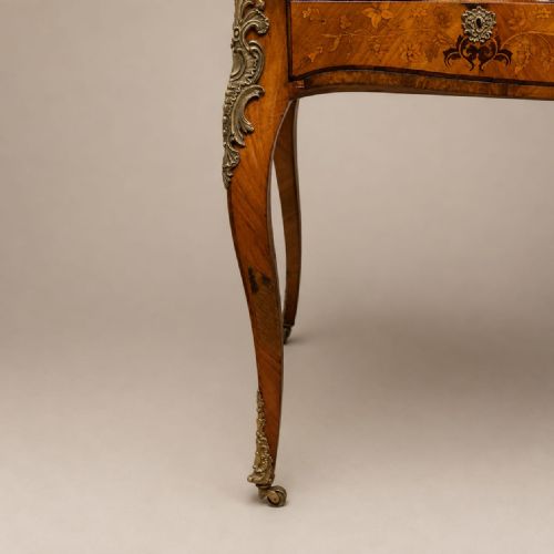 fig 2. A nineteenth-century French walnut writing desk featuring floral marquetry drawers, ornate gilt bronze mounts, and slender cabriole legs.