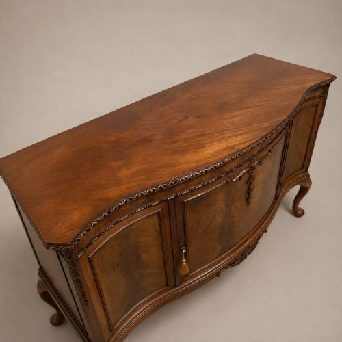fig 1. An Edwardian mahogany side cabinet featuring a serpentine front, detailed carving, cabriole legs, and flame mahogany veneers.