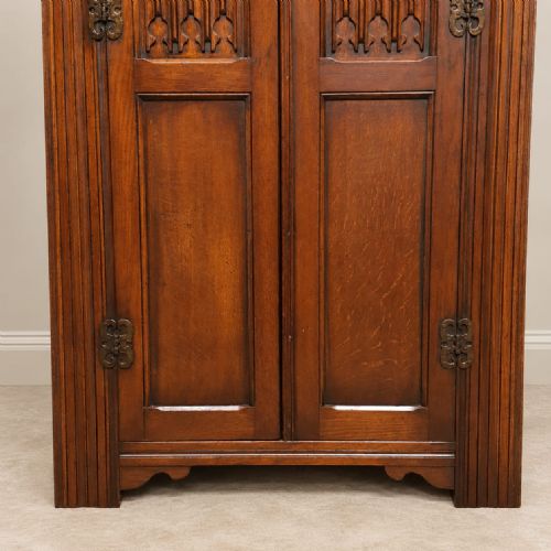 fig 1. A small 1920s oak double wardrobe featuring carved gothic tracery panels, reeded corner pilasters, decorative iron hinges, and a moulded top cornice.