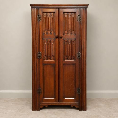 fig 2. A small 1920s oak double wardrobe featuring carved gothic tracery panels, reeded corner pilasters, decorative iron hinges, and a moulded top cornice.