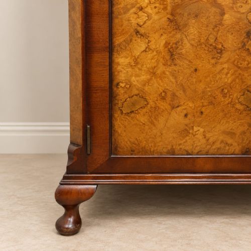 fig 1. A 1920s double-door wardrobe constructed from burr walnut featuring an arched top moulding with carved cresting and short cabriole feet.