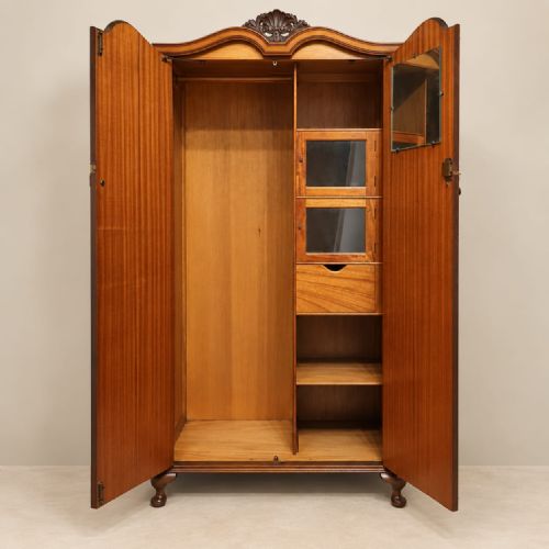 fig 2. A 1920s double-door wardrobe constructed from burr walnut featuring an arched top moulding with carved cresting and short cabriole feet.