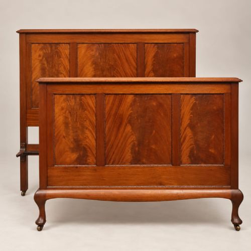 fig 2. An Edwardian mahogany double bedstead featuring flame mahogany panels on the headboard and footboard, raised on front cabriole legs with castors.