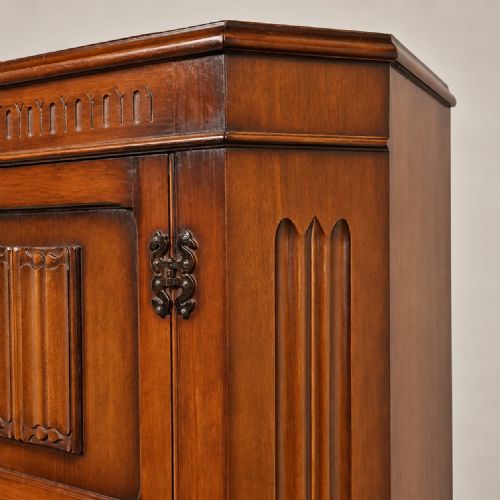 fig 1. A tall brown oak hall wardrobe with a single panelled door featuring carved details, fluted canted corners, and iron hardware.