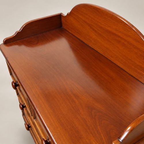 fig 1. A late Victorian mahogany dressing chest featuring an arched backboard upstand, two short drawers over two long drawers with turned wooden handles, set on turned bun feet.