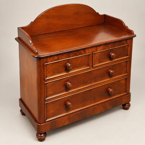 fig 2. A late Victorian mahogany dressing chest featuring an arched backboard upstand, two short drawers over two long drawers with turned wooden handles, set on turned bun feet.