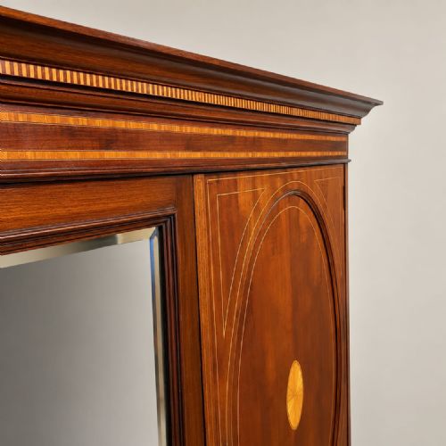 fig 1. An Edwardian mahogany combination wardrobe featuring a full-length mirrored door, an inlaid cupboard, three drawers, and satinwood crossbanding.