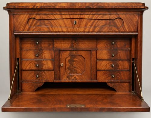 fig 2. A tall 19th-century mahogany Biedermeier secretaire a abattant featuring flame veneer patterns, a central drop-front panel, keyhole escutcheons, and lower drawers.