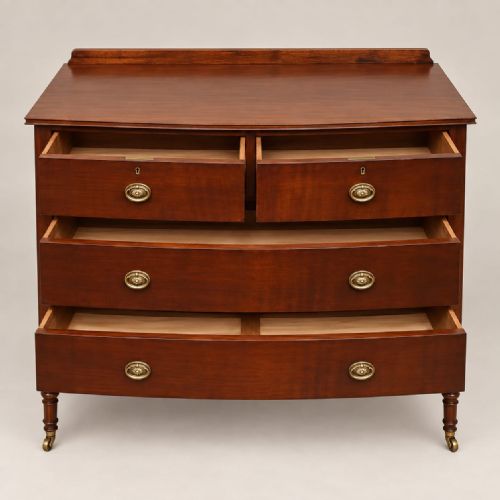 fig 1. A matching pair of mahogany bow-fronted chests featuring three tiers of drawers, brass oval drop handles, low backboards, and turned legs with castors.