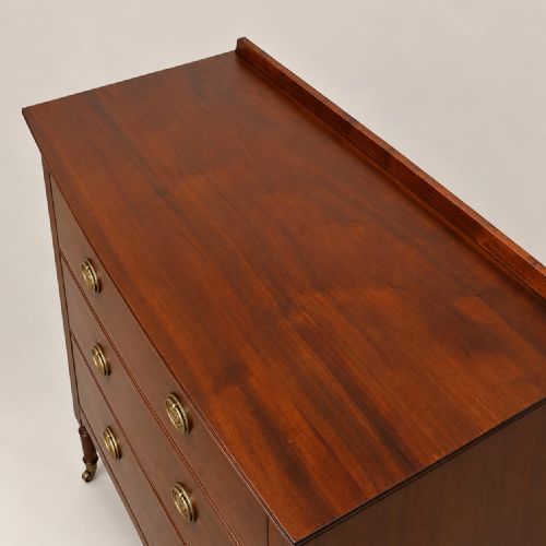 fig 2. A matching pair of mahogany bow-fronted chests featuring three tiers of drawers, brass oval drop handles, low backboards, and turned legs with castors.