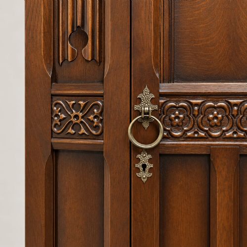 fig 1. A dark oak single-door wardrobe featuring carved floral band detailing, an arched upper panel, vertical linear panelling, and iron hardware.