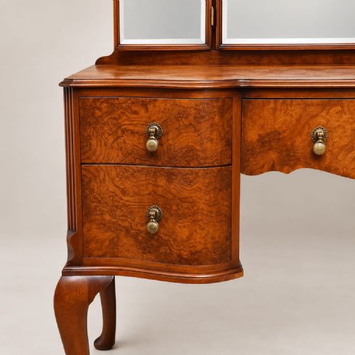 fig 2. A 1920s burr walnut dressing table featuring a serpentine-fronted desk with five drawers, cabriole legs, brass handles, and a three-panel folding mirror.