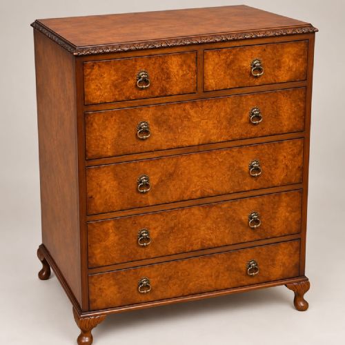 fig 1. A 1920s burr walnut chest of drawers featuring five drawer tiers with brass drop handles and carved cabriole legs.