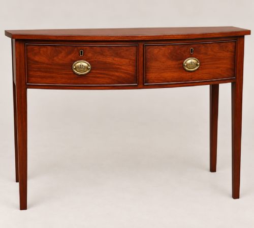 fig 1. A Regency mahogany bow-fronted side table featuring two drawers with brass handles and supported by four tapered legs.