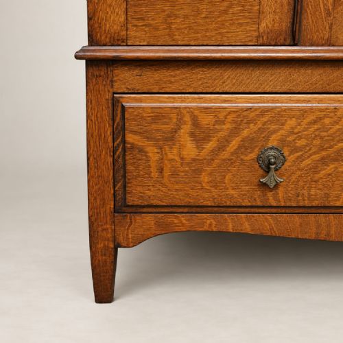 fig 1. A freestanding 1920s oak wardrobe featuring a central mirrored door flanked by two panelled sections above a single lower drawer.