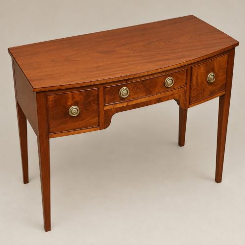 fig 1. A Regency mahogany bowfront side table featuring three drawers with brass ring handles and tapered legs.