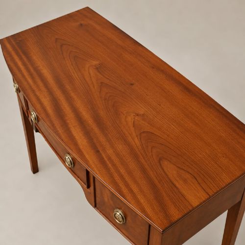 fig 2. A Regency mahogany bowfront side table featuring three drawers with brass ring handles and tapered legs.
