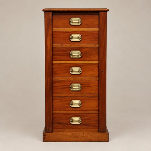 fig 1. A tall mahogany Wellington chest featuring seven drawers with brass handles and a hinged locking bar set on a plinth base.