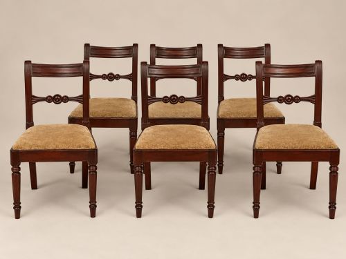 fig 1. A set of six George III mahogany dining chairs featuring carved roundel back splats, turned front legs, and neutral upholstered seats.