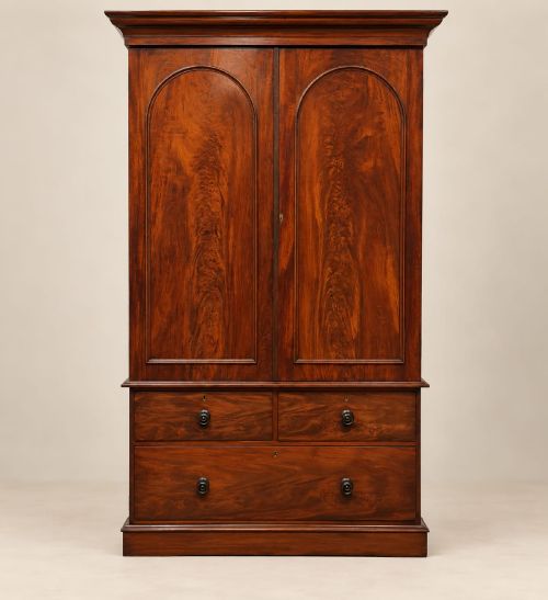 fig 1. A Victorian mahogany double wardrobe featuring two arched panel doors set above a base with two short drawers and one long drawer.