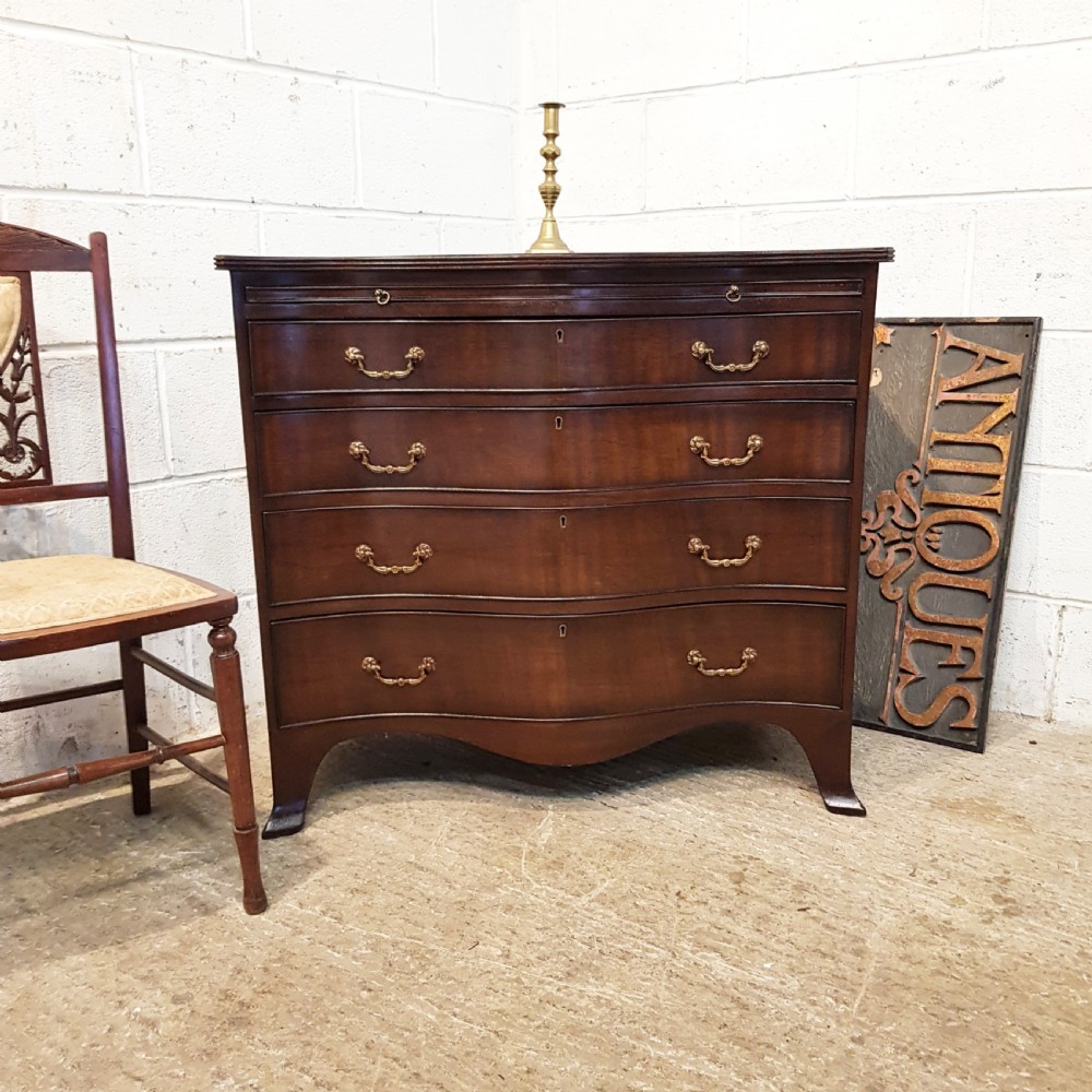 ANTIQUE MAHOGANY SERPENTINE SHAPED CHEST OF DRAWERS WITH BRUSHING SLIDE C1920