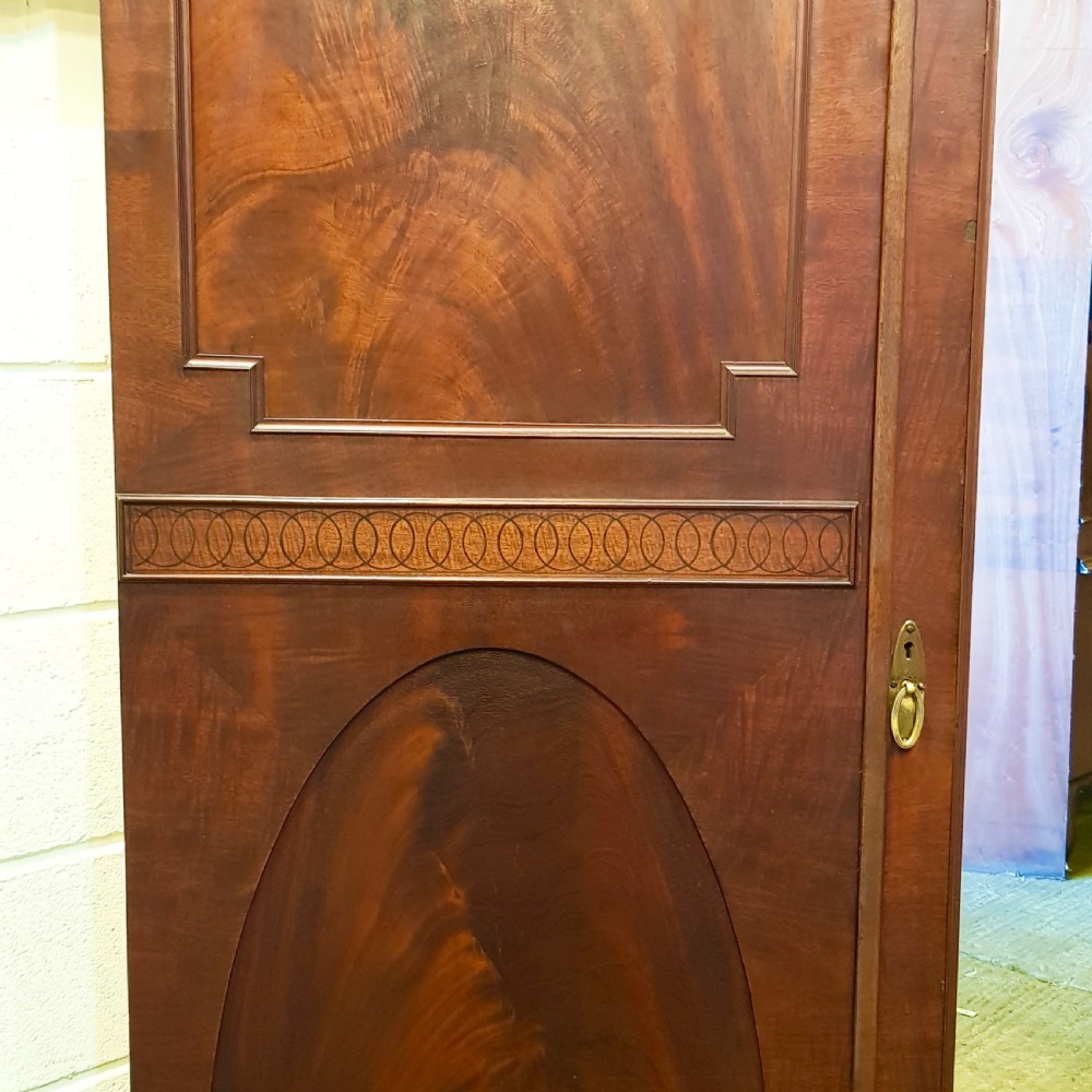 A late Victorian rich mahogany triple wardrobe featuring a central full-length mirrored door flanked by two flame mahogany panelled doors topped by a classical cornice. View V