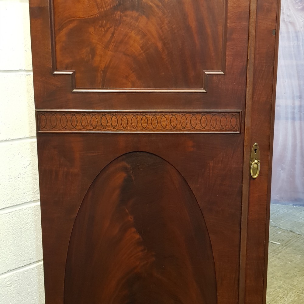 A late Victorian rich mahogany triple wardrobe featuring a central full-length mirrored door flanked by two flame mahogany panelled doors topped by a classical cornice. View VI